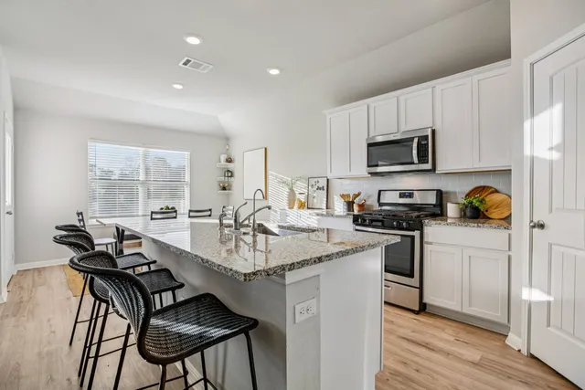 a kitchen with stainless steel appliances a stove a sink a microwave a refrigerator and cabinets