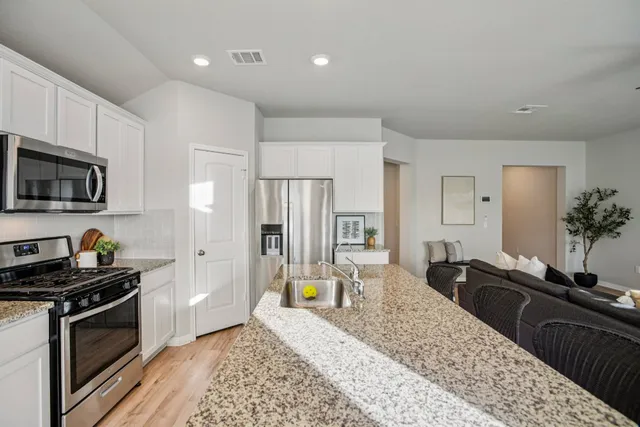 a large kitchen with granite countertop a sink and a stove top oven
