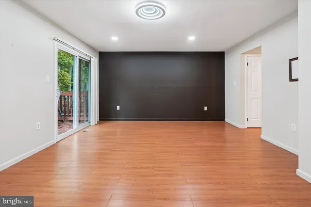 a view of an empty room with wooden floor and windows