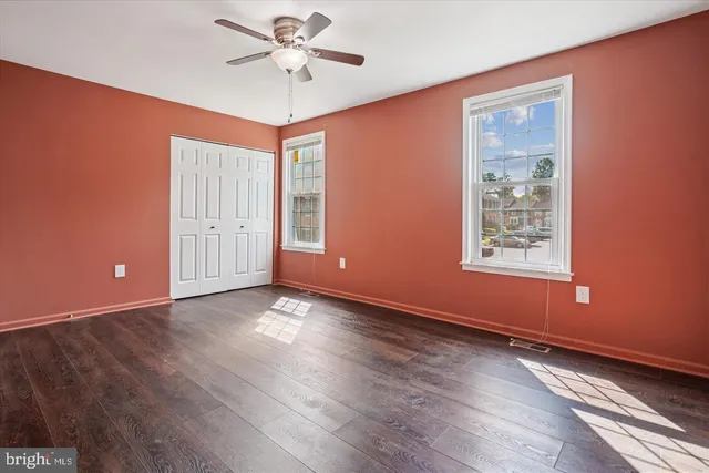 a view of an empty room with a window and wooden floor