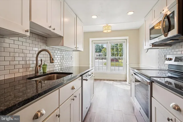 a kitchen with granite countertop a sink stainless steel appliances and cabinets