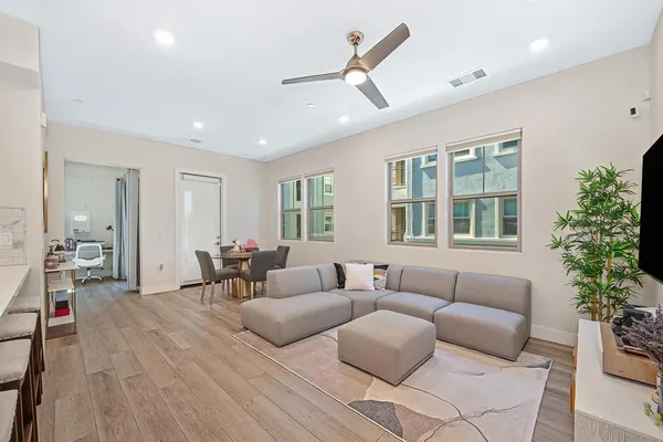 a living room with furniture a wooden floor and a ceiling fan