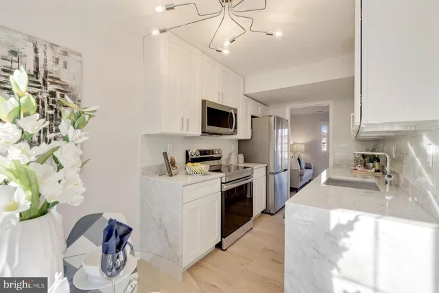 a kitchen with stainless steel appliances granite countertop a sink a stove top oven a chimney and a counter top space