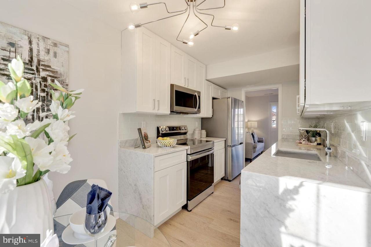 4940 Bradley Boulevard, Unit 247 Chevy Chase, MD 20815 - Photo 9 of 25 a kitchen with stainless steel appliances granite countertop a sink a stove top oven a chimney and a counter top space