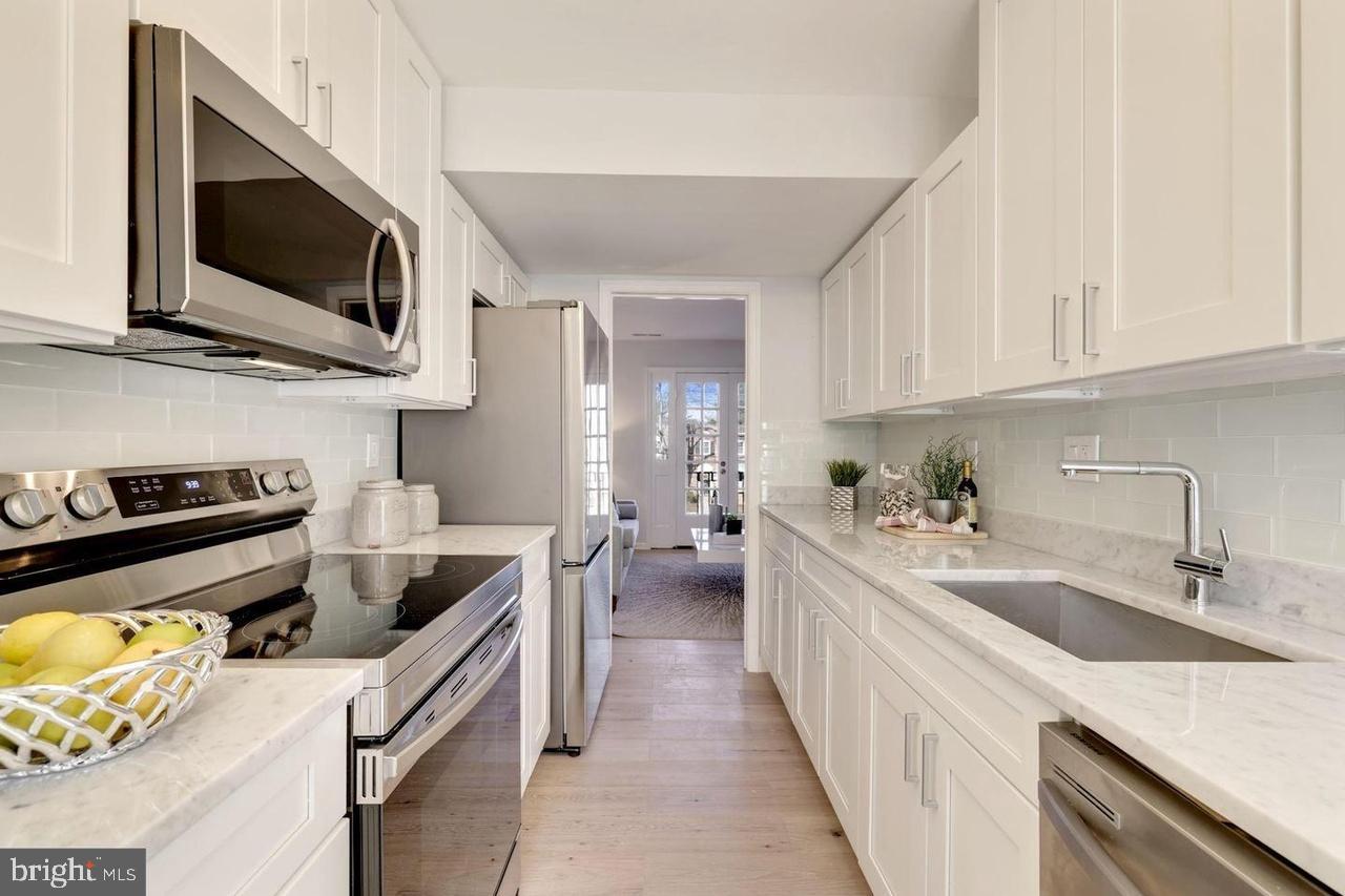 4940 Bradley Boulevard, Unit 247 Chevy Chase, MD 20815 - Photo 10 of 25 a kitchen with stainless steel appliances a stove a sink and a microwave
