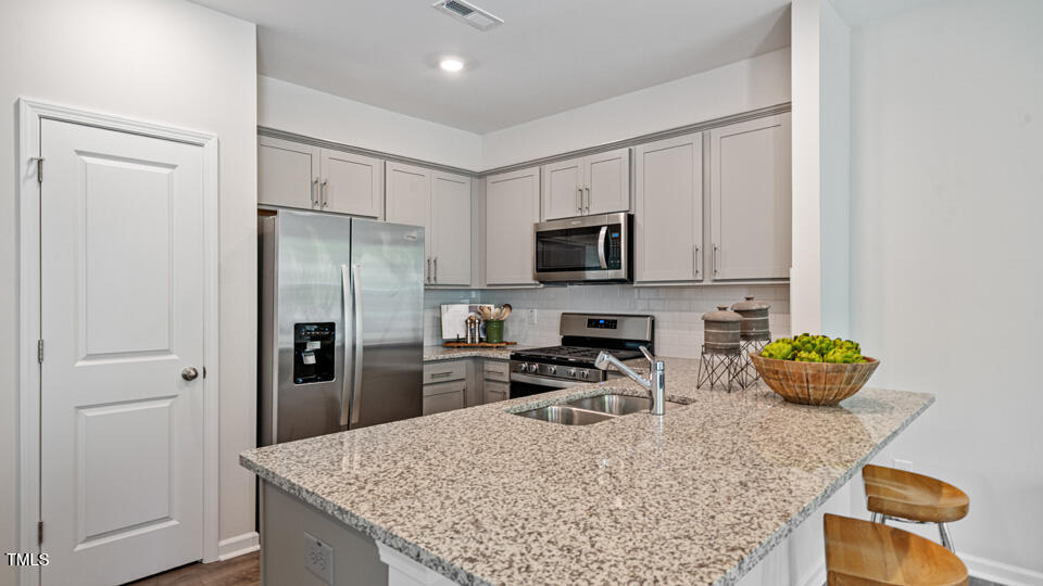 405 Belgian Red Way Rolesville, NC 27571 - Photo 7 of 28 a kitchen with stainless steel appliances granite countertop a refrigerator a stove a sink a counter space and cabinets