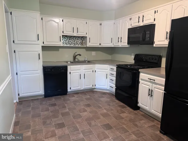 a kitchen with granite countertop a refrigerator stove and sink
