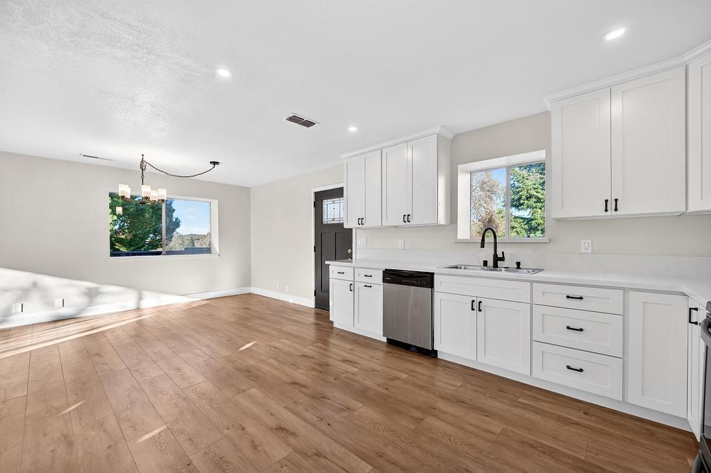 3901 Luneman Road Placerville, CA 95667 - Photo 7 of 56 a kitchen with granite countertop a stove a sink and white cabinets with wooden floor