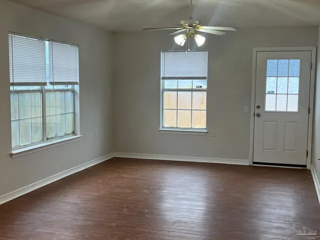 an empty room with wooden floor chandelier and windows
