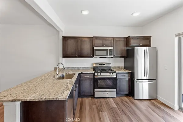 a kitchen with granite countertop stainless steel appliances a refrigerator a stove top oven a sink and dishwasher