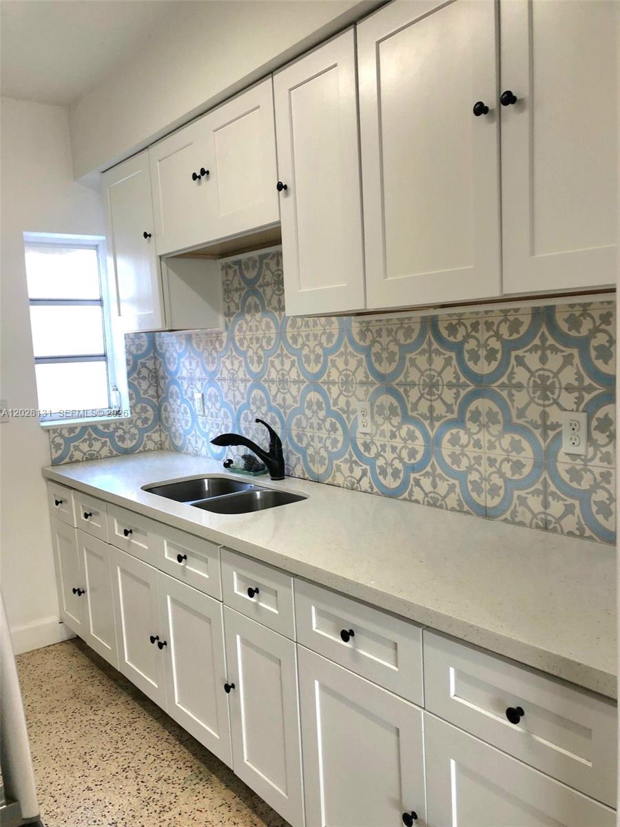 7135 Rue Granville, Unit 4 Miami Beach, FL 33141 - Photo 2 of 9 a kitchen with white cabinets and sink