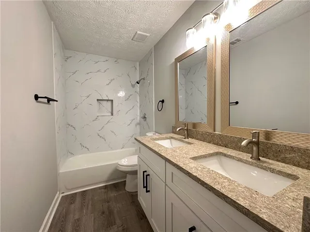 a bathroom with a granite countertop sink toilet and shower