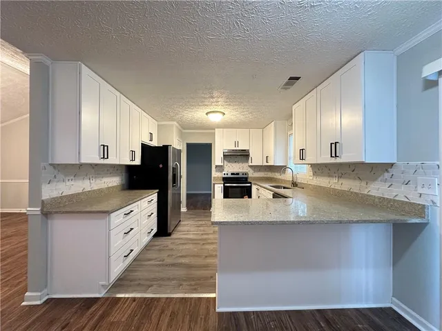 a large kitchen with stainless steel appliances kitchen island a large counter top and wooden floors