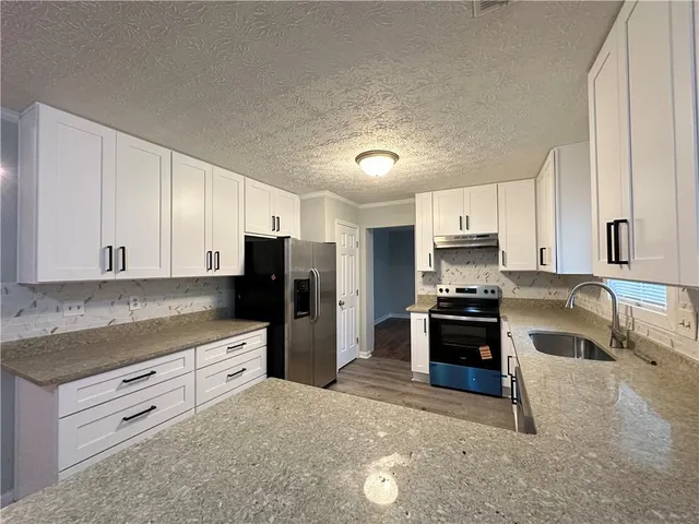 a kitchen with stainless steel appliances granite countertop a stove refrigerator and a sink