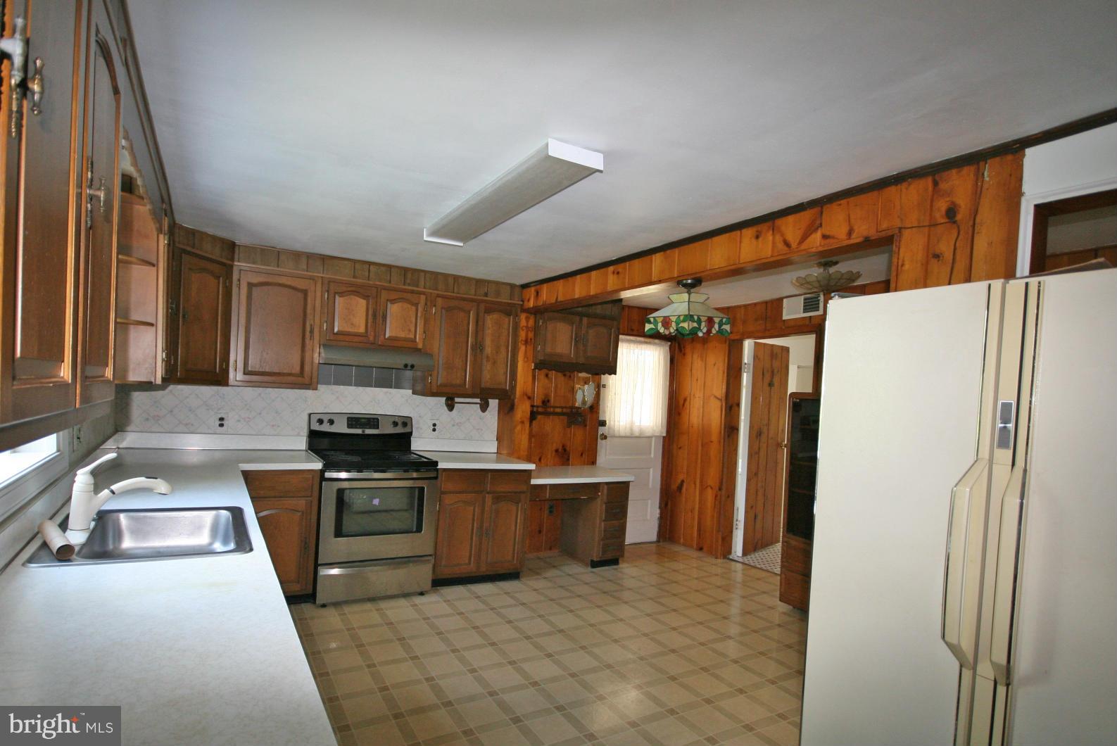 4406 Maple Road Morningside, MD 20746 - Photo 5 of 19 a kitchen with stainless steel appliances granite countertop a refrigerator a stove and a sink with wooden floor