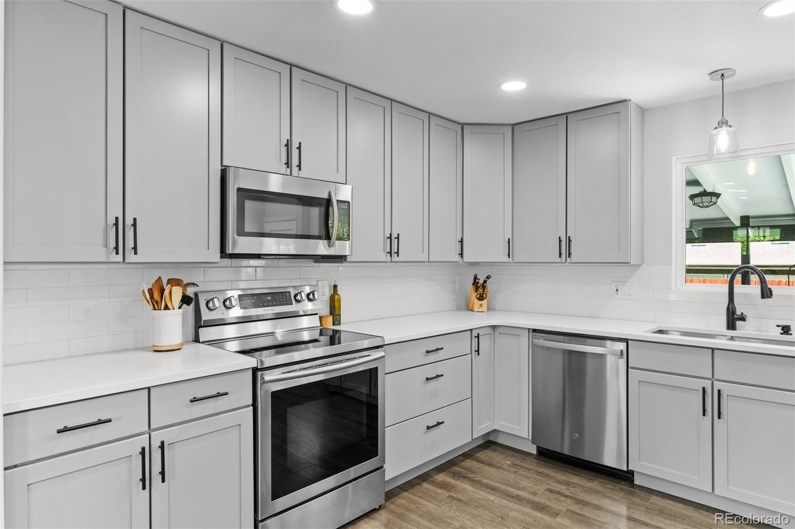 6000 Garrison Street Arvada, CO 80004 - Photo 14 of 50 a kitchen with white cabinets stainless steel appliances and sink