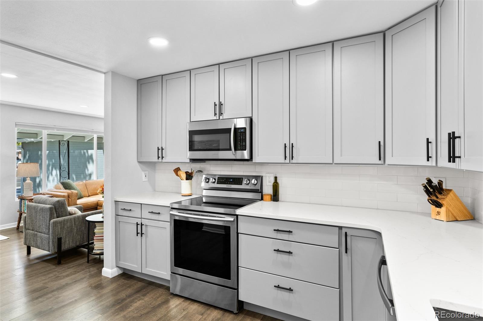 6000 Garrison Street Arvada, CO 80004 - Photo 15 of 50 a kitchen with stainless steel appliances white cabinets and wooden floor