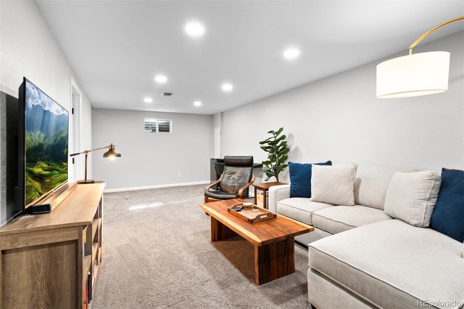 6000 Garrison Street Arvada, CO 80004 - Photo 25 of 50 a living room with furniture a flat screen tv and a floor to ceiling window