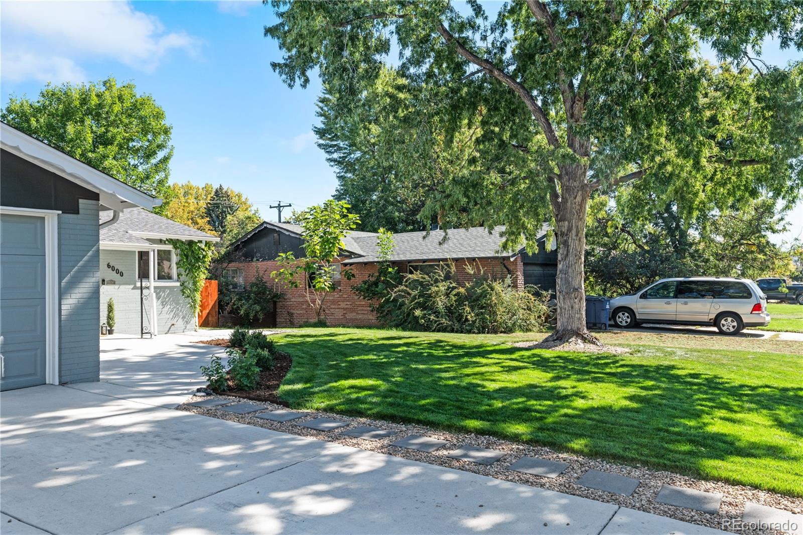 6000 Garrison Street Arvada, CO 80004 - Photo 3 of 50 a front view of a house with a garden and trees