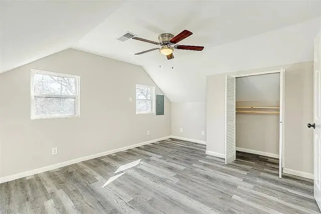 a view of empty room with wooden floor and fan