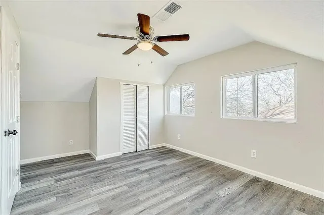 a view of empty room with wooden floor and fan