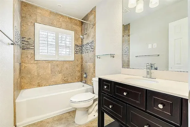 a bathroom with a granite countertop toilet a sink a bathtub and a large mirror