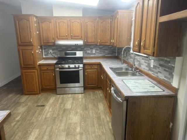 1100 Pine Top Road Toone, TN 38381 - Photo 7 of 40 Kitchen featuring wood-finish cabinetry, stainless steel appliances, a double basin sink with a high-arc faucet, and a mosaic tile backsplash