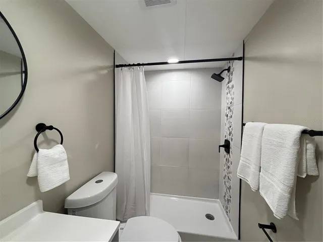 a bathroom with a shower a toilet and a mirror