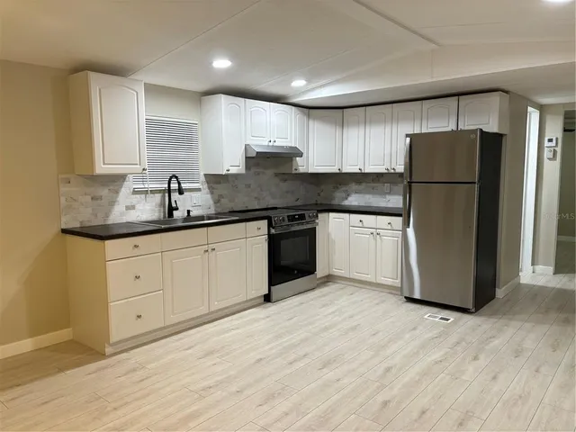a kitchen with stainless steel appliances granite countertop a refrigerator sink and cabinets