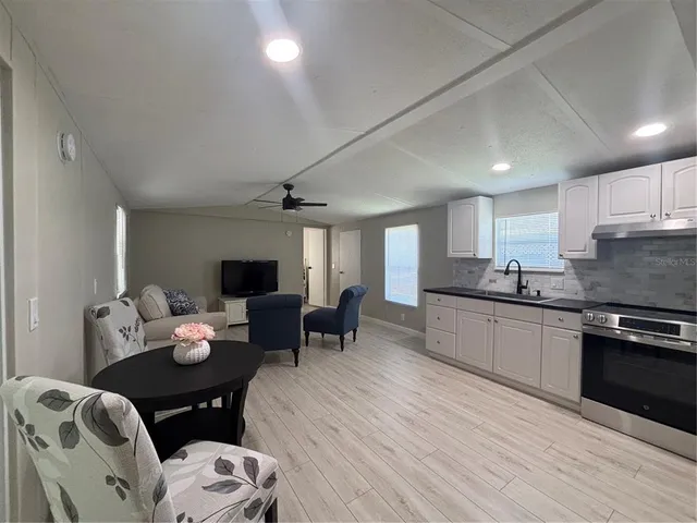 a living room with furniture kitchen view and a wooden floor