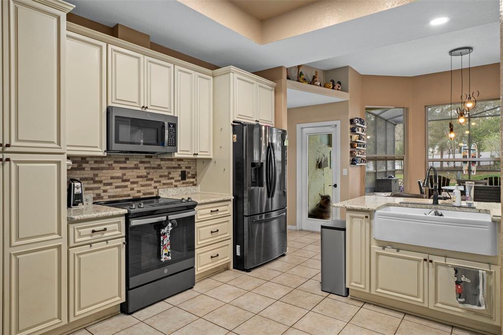 1378 Matthew Avenue Spring Hill, FL 34609 - Photo 14 of 56 a kitchen with stainless steel appliances granite countertop a stove a refrigerator and a microwave