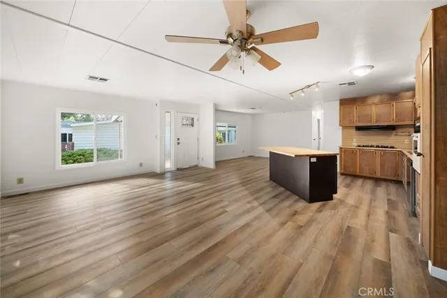 a large kitchen with stainless steel appliances kitchen island granite countertop a refrigerator a stove and a sink with wooden cabinets