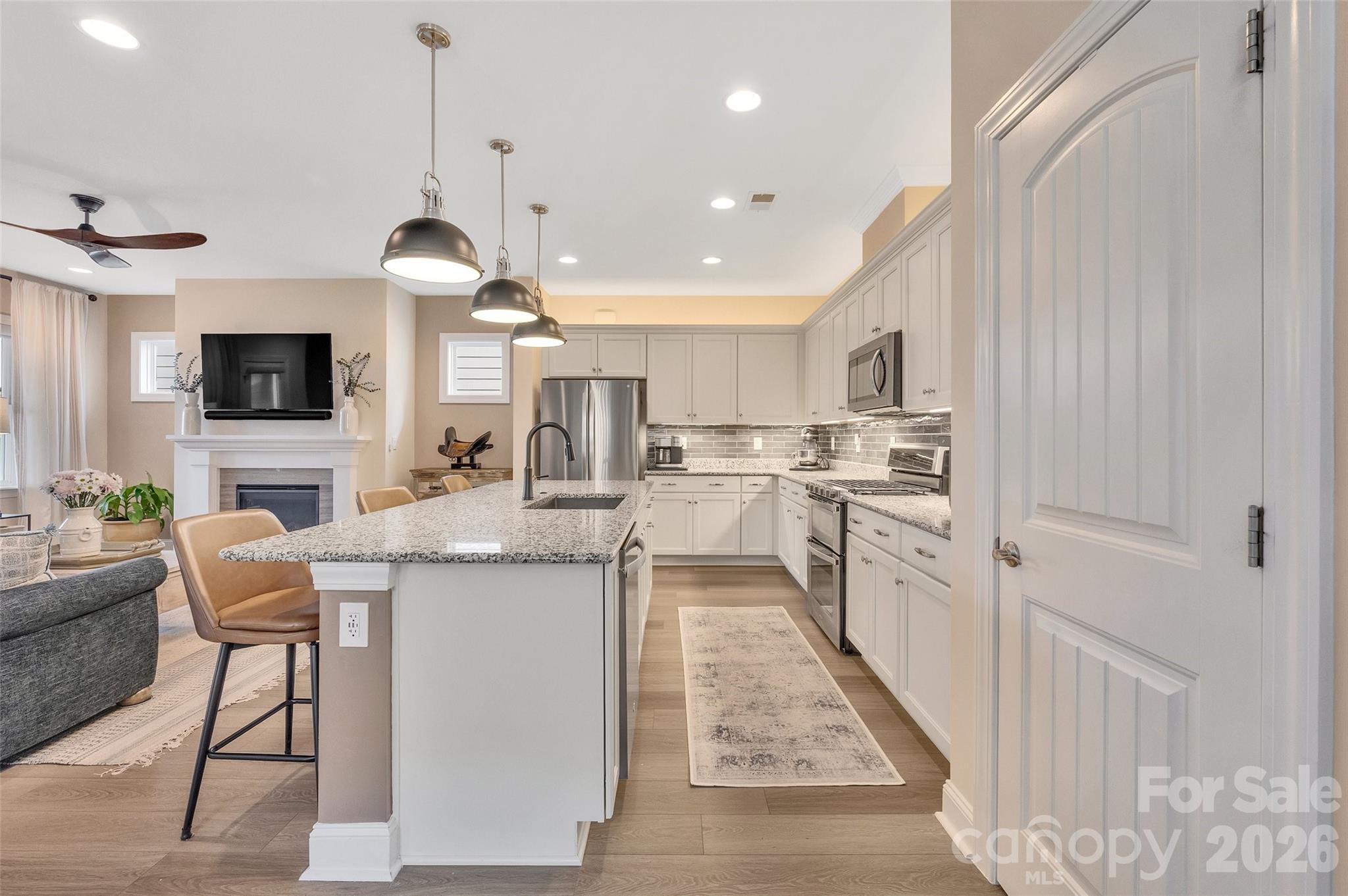 6243 Scuttle Lane Denver, NC 28037 - Photo 11 of 34 a kitchen with stainless steel appliances kitchen island granite countertop a stove top oven a sink dishwasher a dining table and chairs with wooden floor