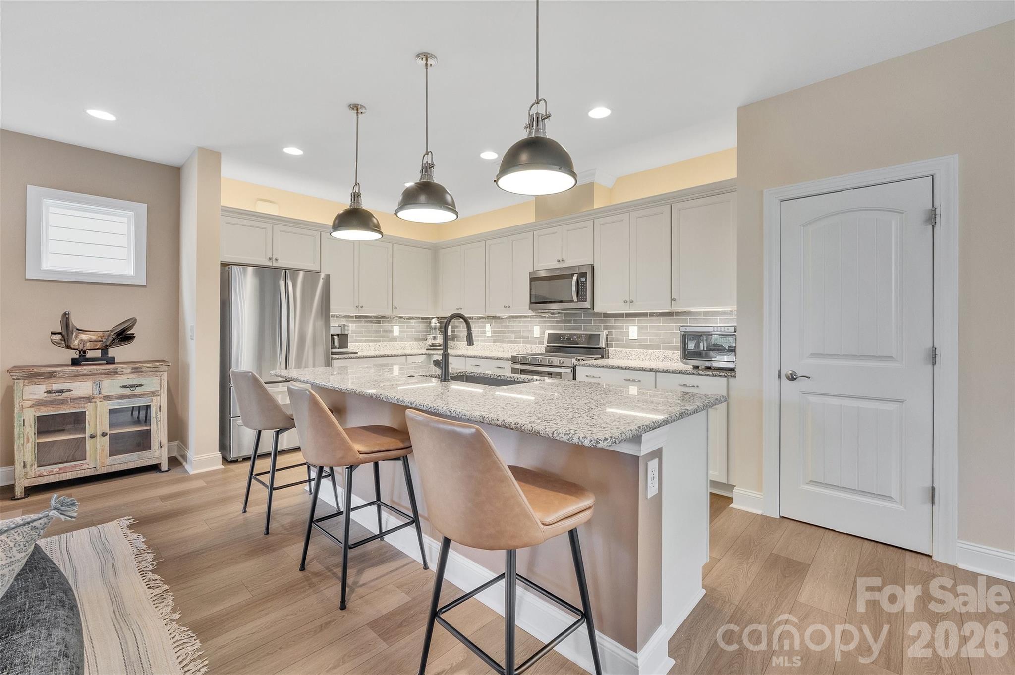 6243 Scuttle Lane Denver, NC 28037 - Photo 12 of 34 a kitchen with stainless steel appliances kitchen island granite countertop a table chairs and a refrigerator