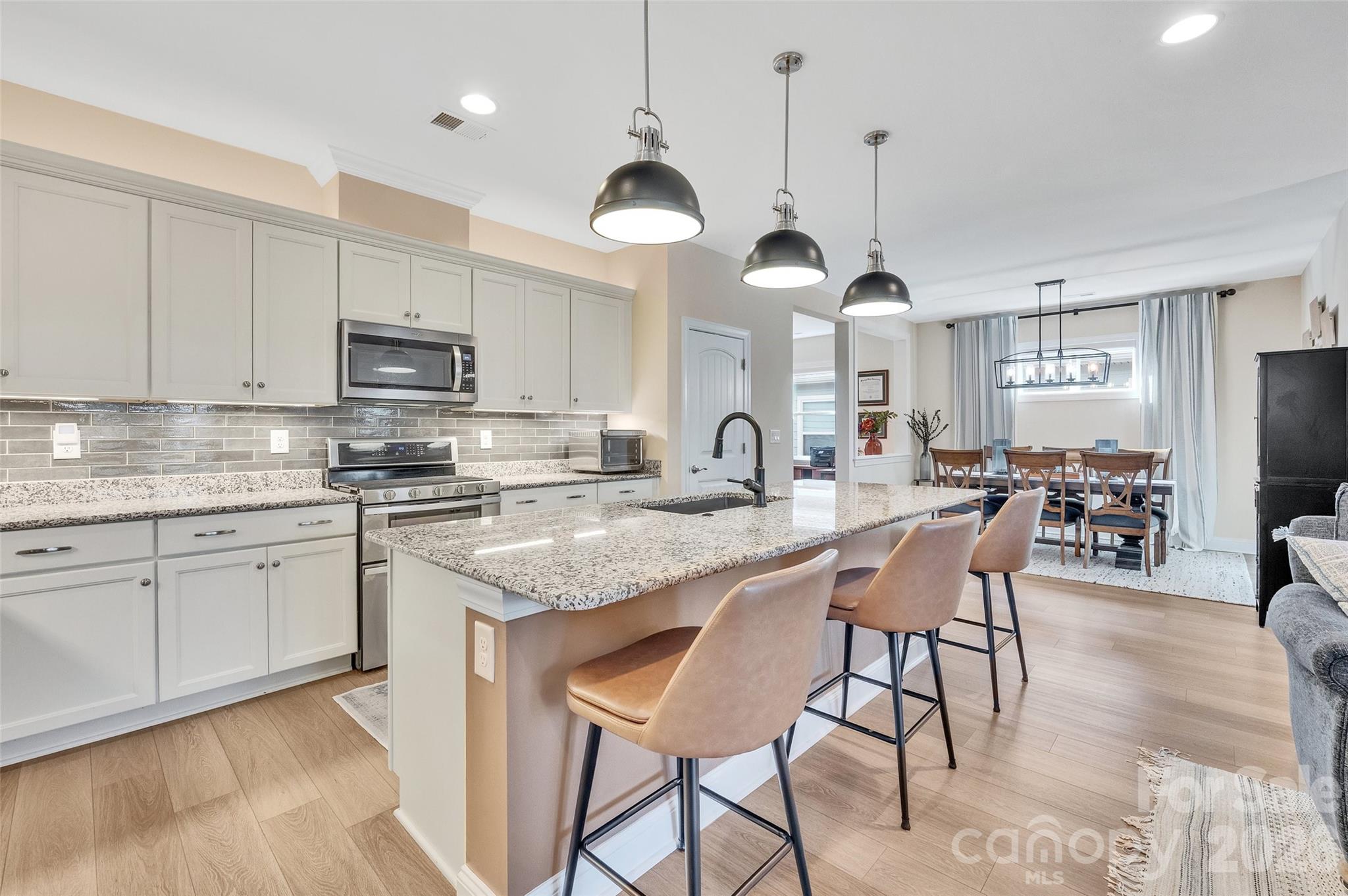6243 Scuttle Lane Denver, NC 28037 - Photo 13 of 34 a kitchen with stainless steel appliances granite countertop a stove a sink a dining table and chairs with wooden floor