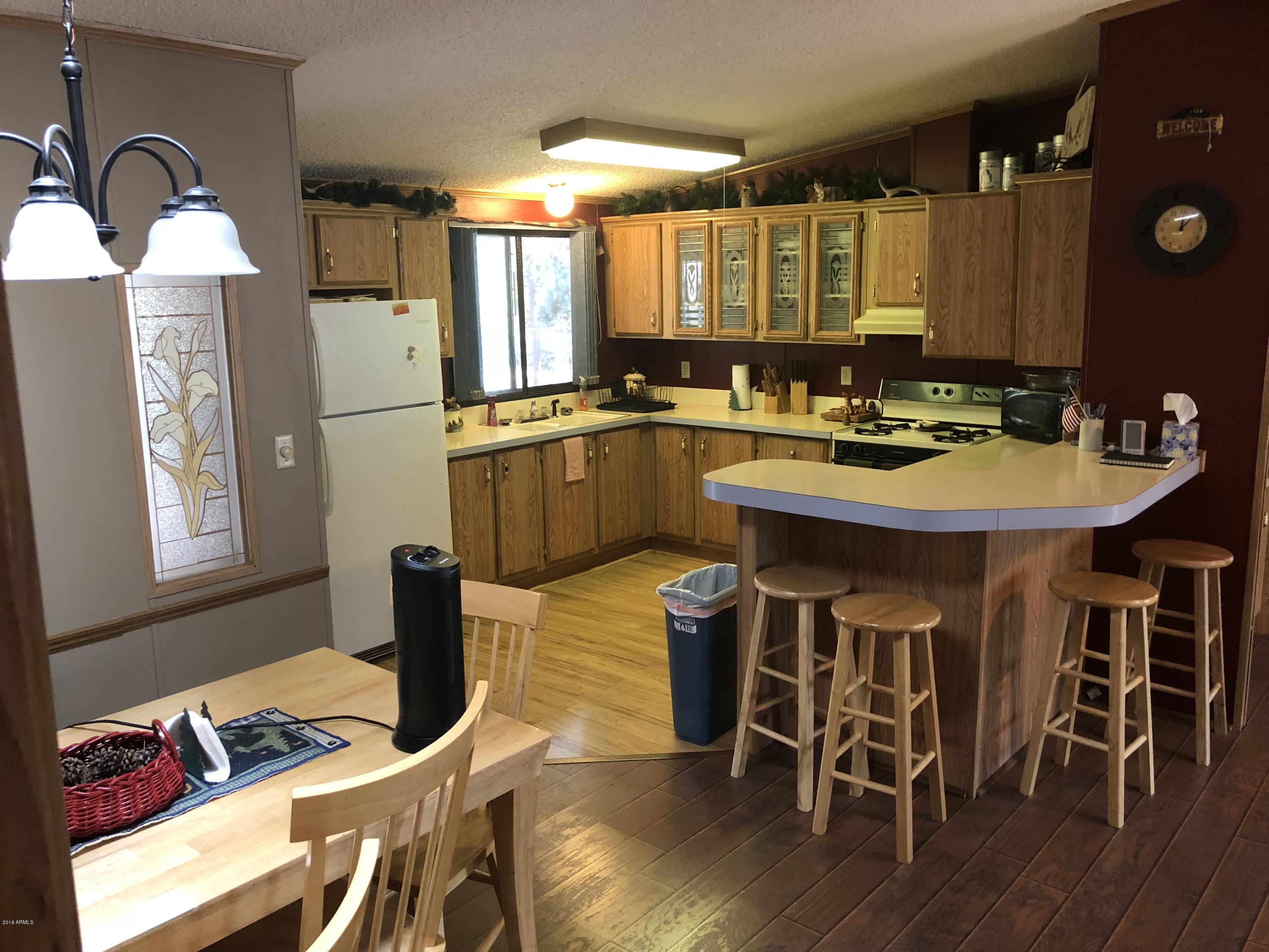 2865 Cattle Trail Road Overgaard, AZ 85933 - Photo 11 of 28 a kitchen with a sink chairs and wooden floor