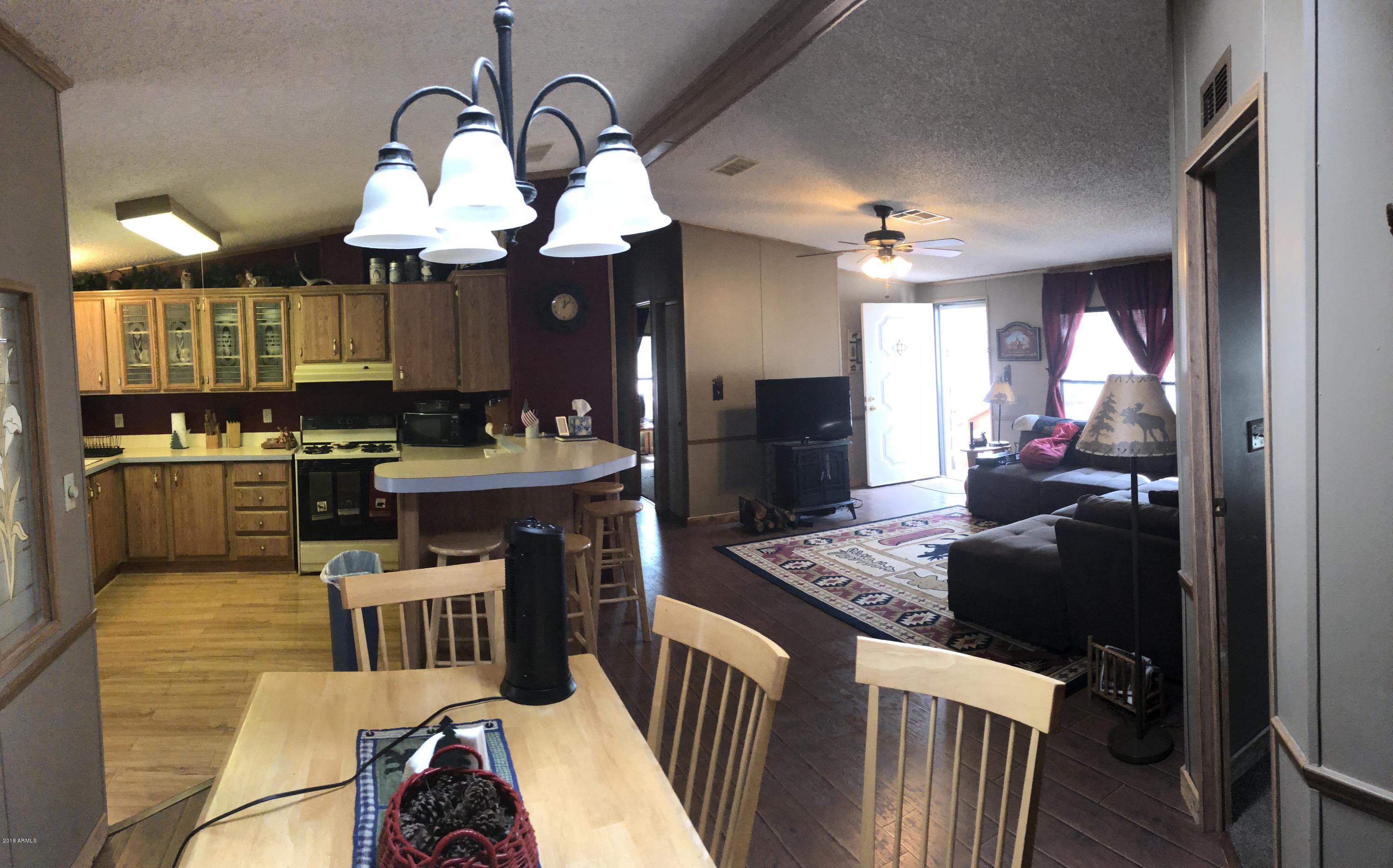 2865 Cattle Trail Road Overgaard, AZ 85933 - Photo 13 of 28 a kitchen with stainless steel appliances granite countertop a stove top oven a sink dishwasher and couches with wooden floor