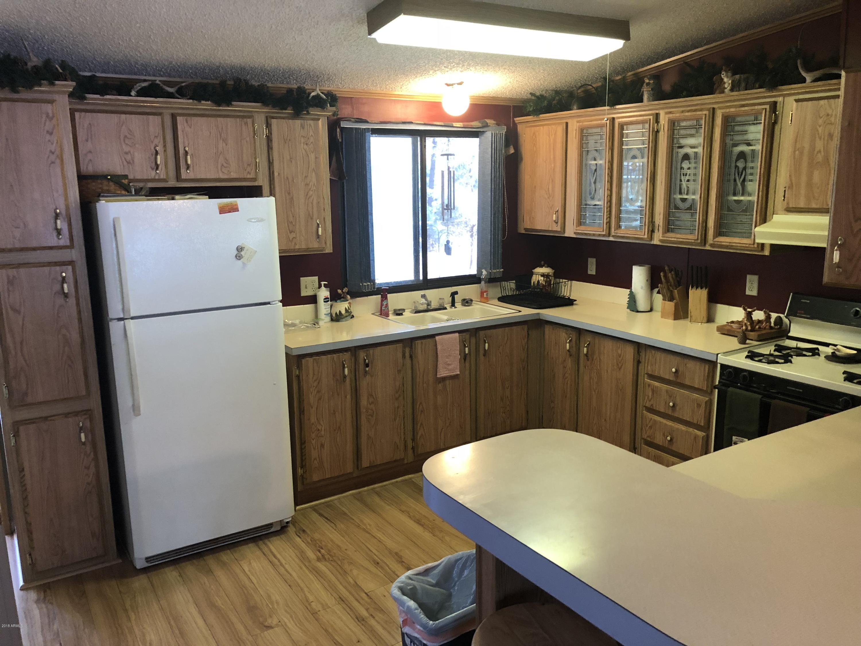 2865 Cattle Trail Road Overgaard, AZ 85933 - Photo 14 of 28 a kitchen with a sink a refrigerator and cabinetry