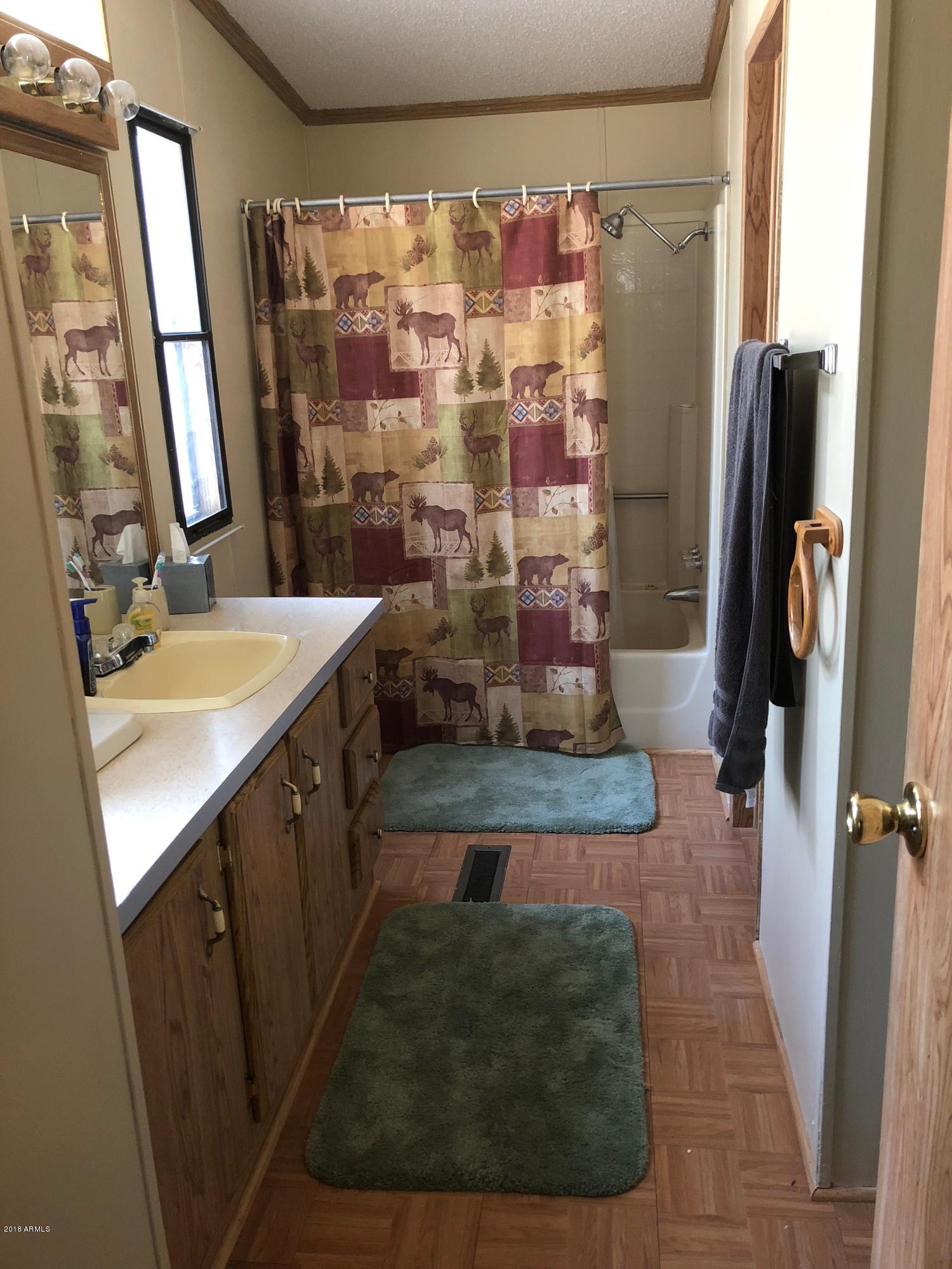2865 Cattle Trail Road Overgaard, AZ 85933 - Photo 20 of 28 a bathroom with a granite countertop sink a mirror and shower