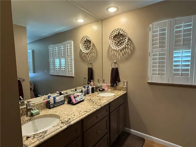 a bathroom with double vanity sinks a mirror and a window