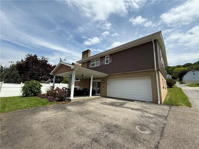 a front view of house and yard with beautiful flowers and green space