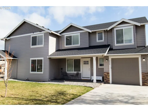 a view of a yard in front of a house with large windows