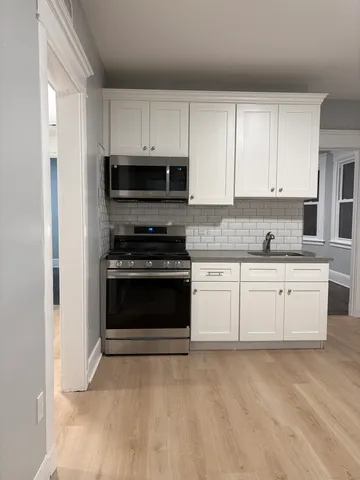 a kitchen with granite countertop white cabinets and stainless steel appliances