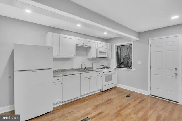 a kitchen with granite countertop white cabinets and white appliances