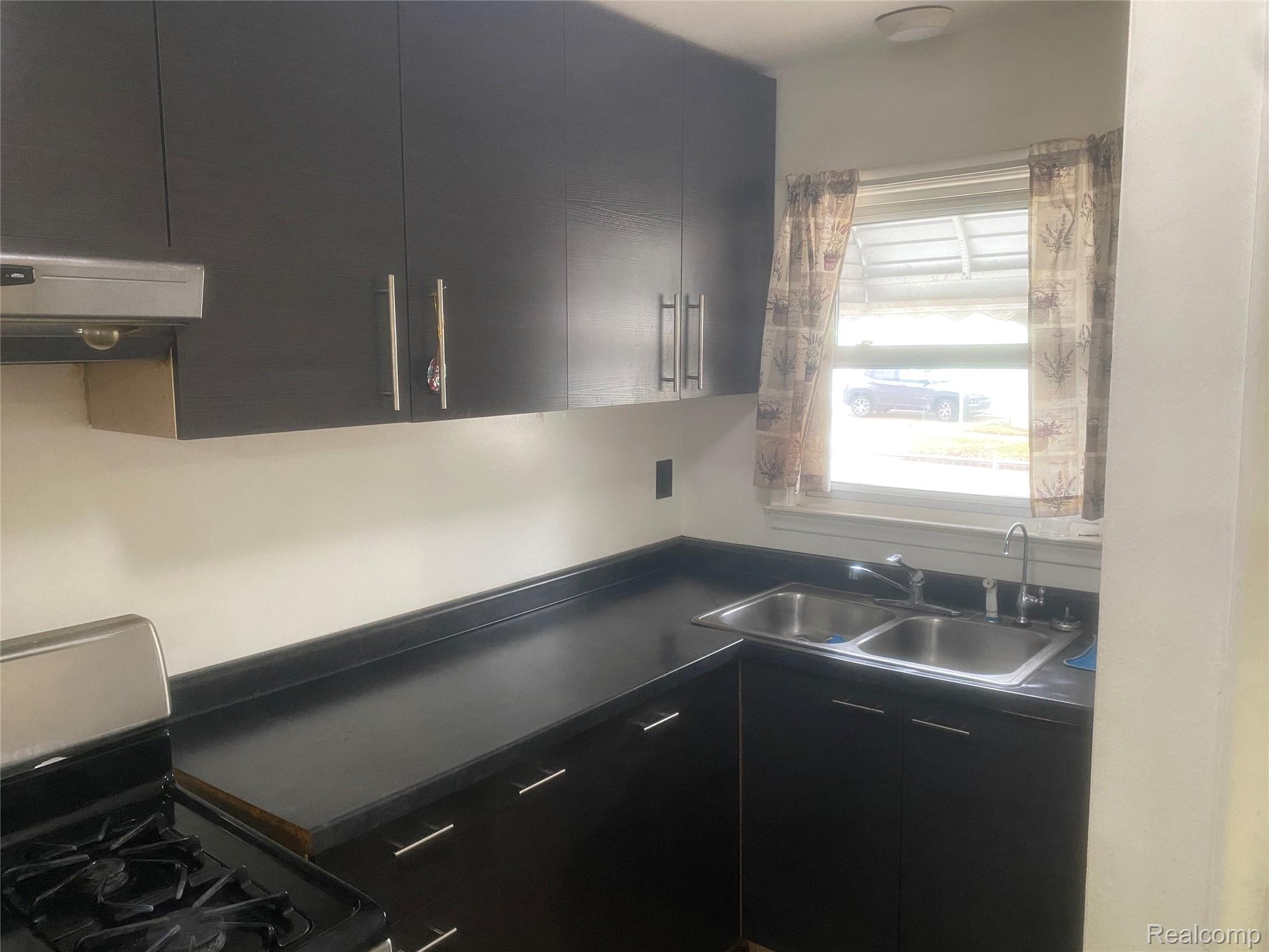 180 West Rutgers Avenue Pontiac, MI 48340 - Photo 12 of 33 Kitchen with dark cabinetry, dark countertops, black gas range, and modern cabinets