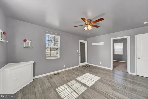 a view of an empty room with window and wooden floor