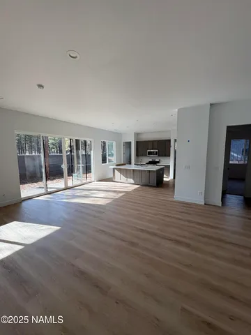 a large white kitchen with stainless steel appliances kitchen island granite countertop a refrigerator and a stove top oven