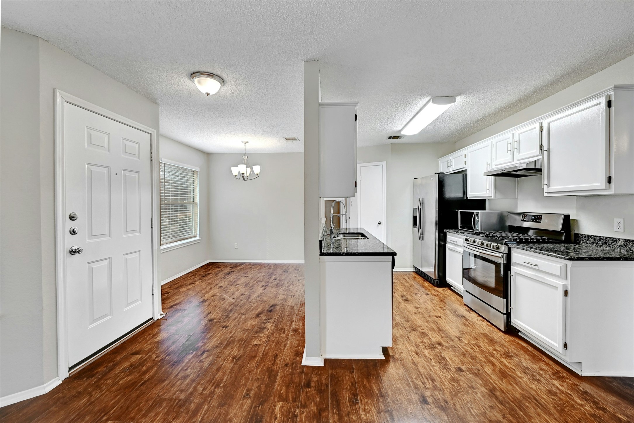 1807 Hollow Tree Boulevard Round Rock, TX 78681 - Photo 11 of 40 a kitchen with granite countertop a stove top oven a sink dishwasher and a refrigerator with wooden floor