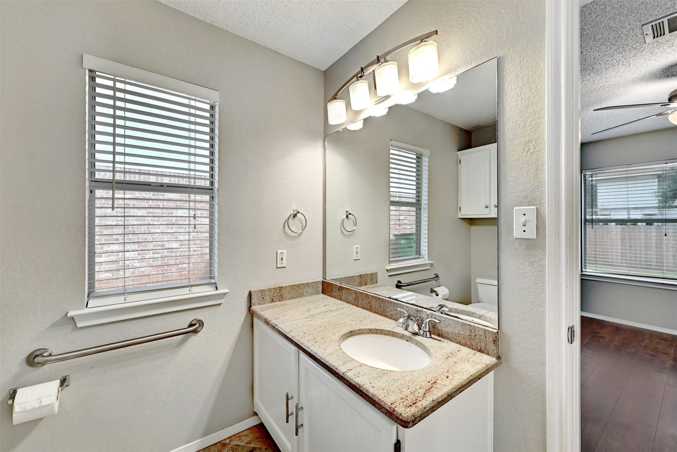 1807 Hollow Tree Boulevard Round Rock, TX 78681 - Photo 24 of 40 a bathroom with a granite countertop sink a toilet and a mirror