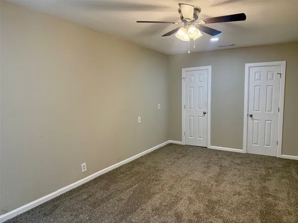 an empty room with closet and a chandelier fan